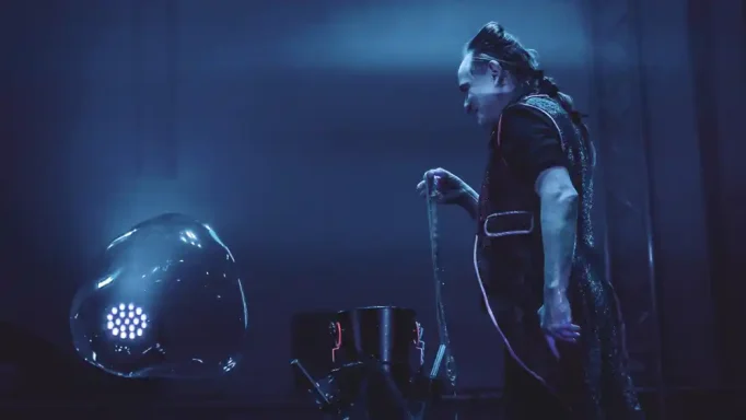 Seiufenblase aus Schlaufe Seifenblasenshow Festung Ehrenbreitstein Ein Mensch steht in einem dunklen Raum mit blauer Beleuchtung und einem futuristischen Gerät.