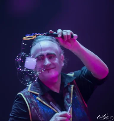 Viereckige Seifenblasen Stephan Masur Festungsvarieté Zauberkünstler mit einer Seifenblase und buntem Licht im Hintergrund.